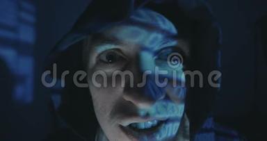 关闭疯狂黑客程序员在引擎盖与二进制代码反射在他的脸在黑暗的房间晚上。 肖像